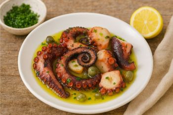 Παραδοσιακό χταπόδι ξιδάτο κομμένο σε μπουκιές, σε πιάτο με ελαιόλαδο, ξίδι και φύλλα δάφνης